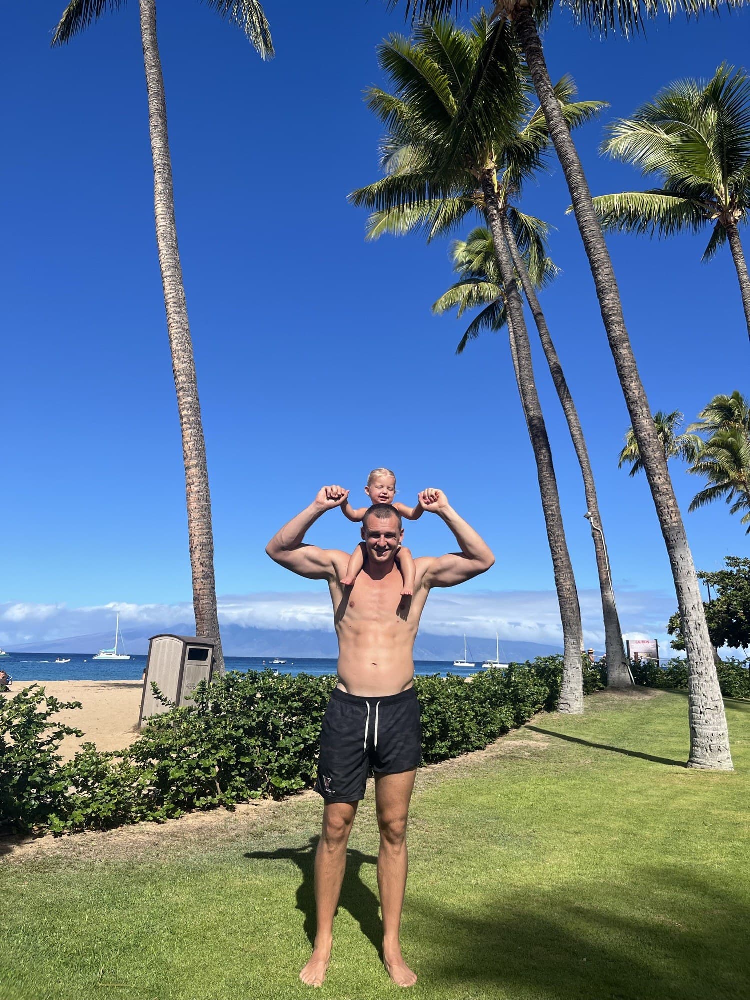 Kyle Collinsworth on the beach with his child on his shoulders
